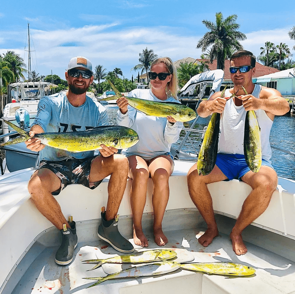 Group displaying mahi mahi aboard boat at tropical marina