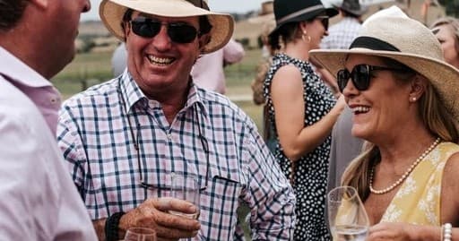 Guests enjoying outdoor wine tasting at sunlit vineyard event