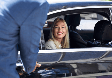 Private car transfer driver assisting passenger at airport curbside