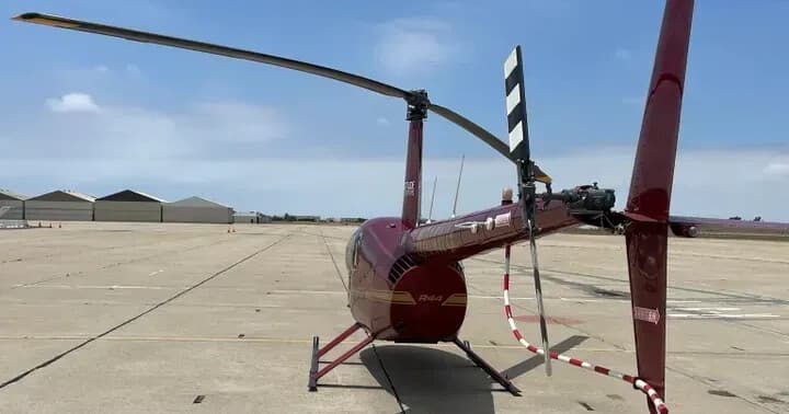 Rear view of red helicopter on airport ramp, maintenance tape