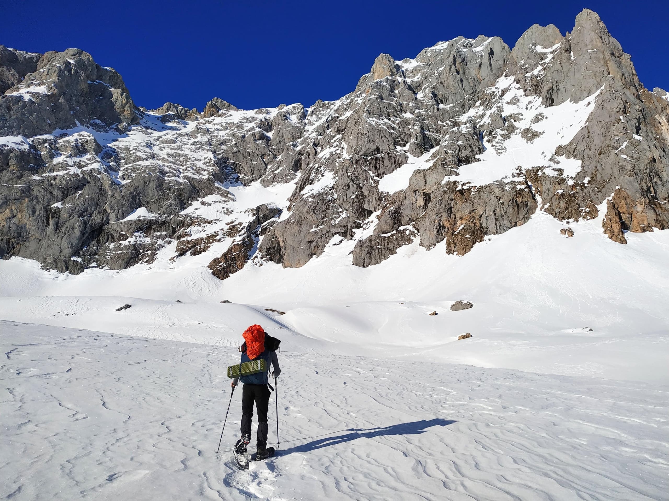 Backcountry skier traversing snowy alpine cirque and peaks