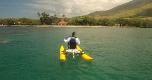 Rider on yellow outrigger water bike off Hawaiian coastline
