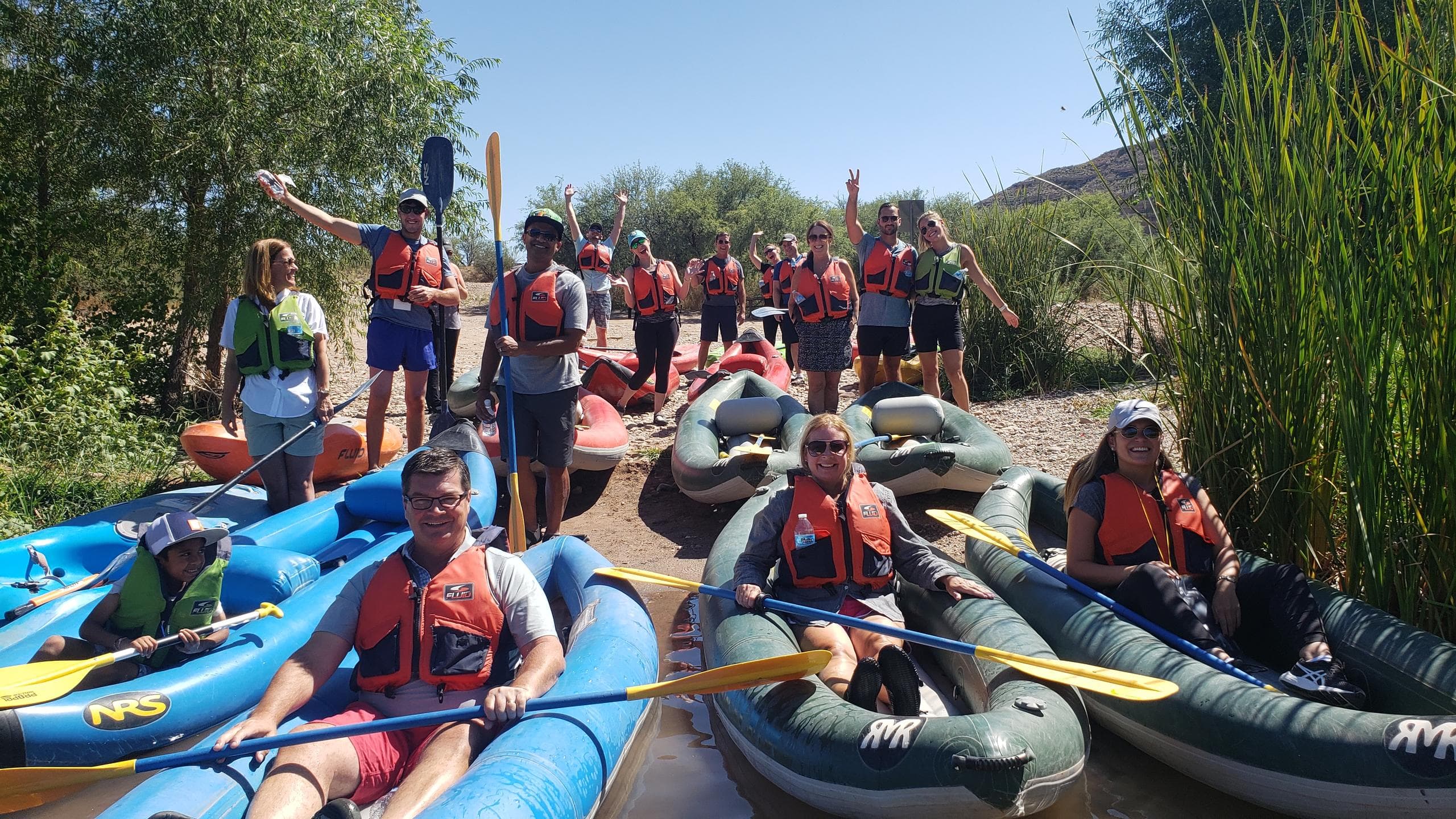 Large flotilla of kayaks launching on scenic river for guided tour