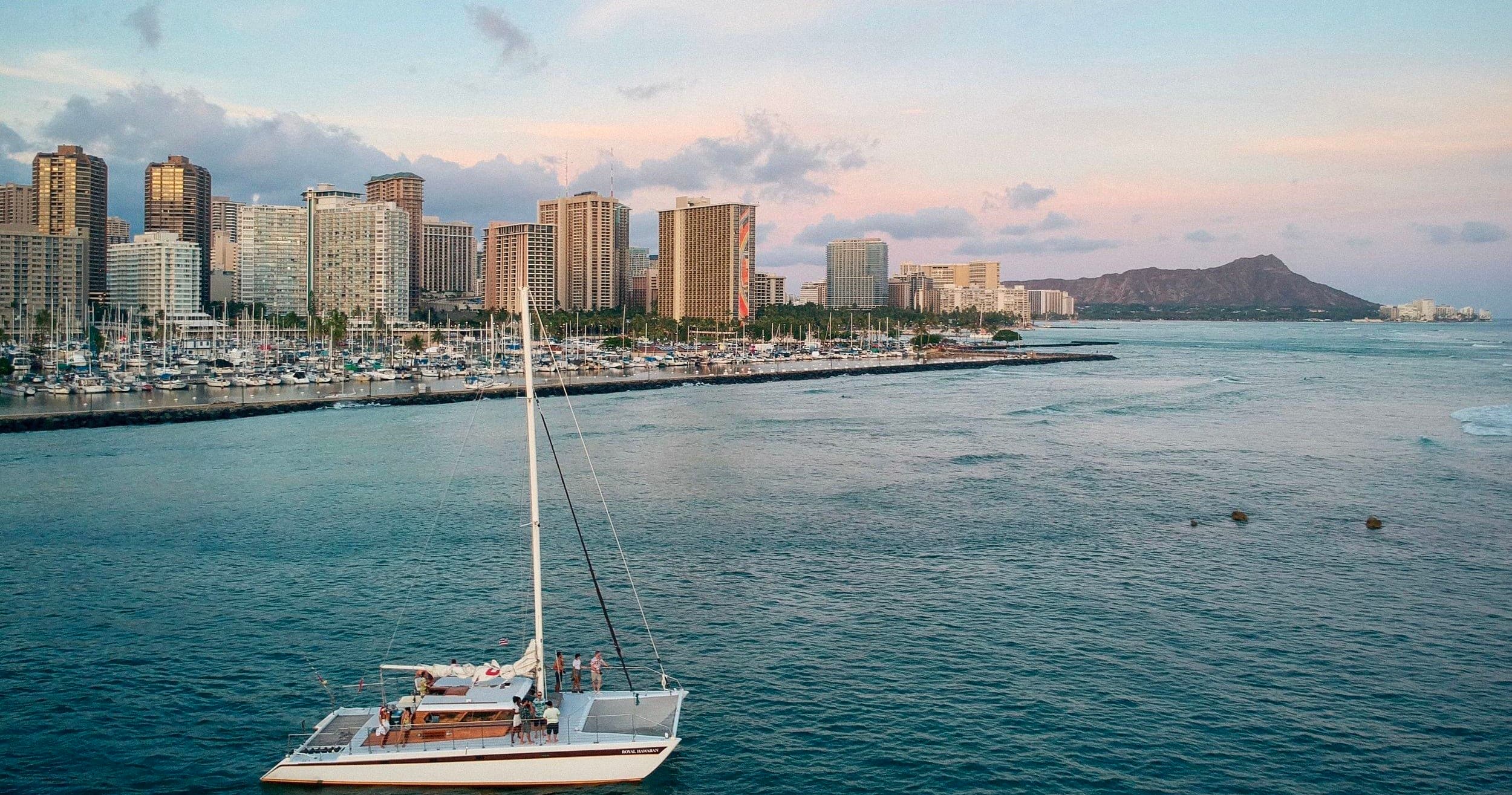 Sailboat near Waikiki skyline at calm oceanfront harbor