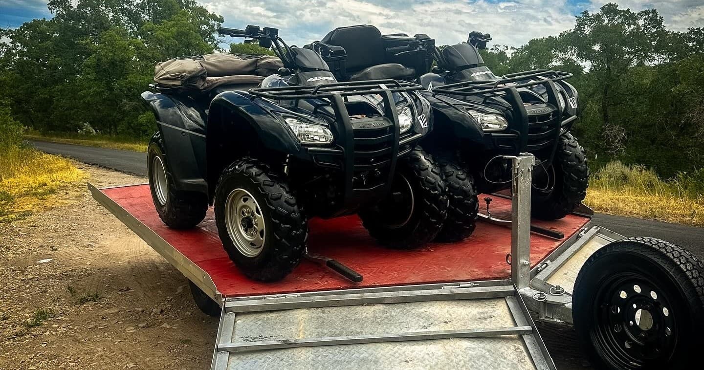 All-terrain vehicles loaded on trailer at rural trailhead parking