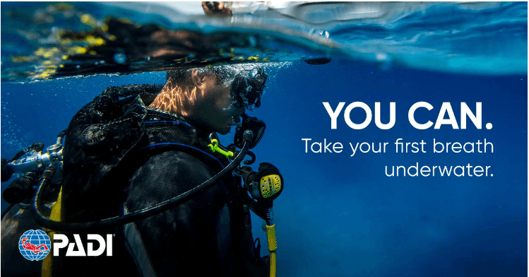 Scuba diver exploring clear blue ocean taking initial breath
