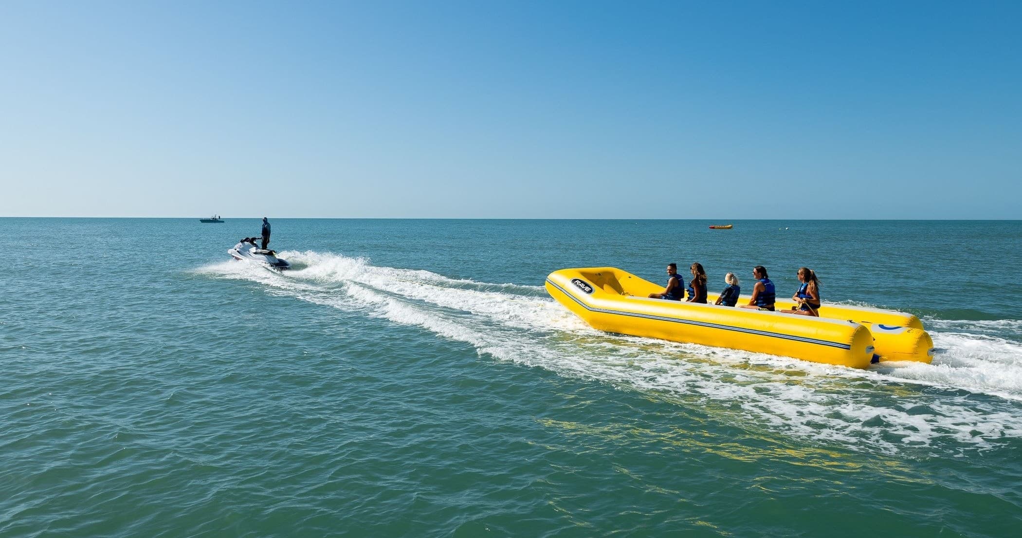 Speedboat towing yellow inflatable banana boat on ocean