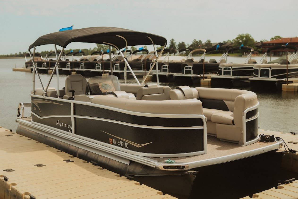 Spacious pontoon boat docked on tranquil lake for rentals