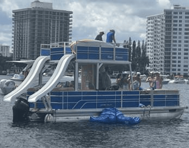 Pontoon party boat with water slides near city waterfront, boating fun