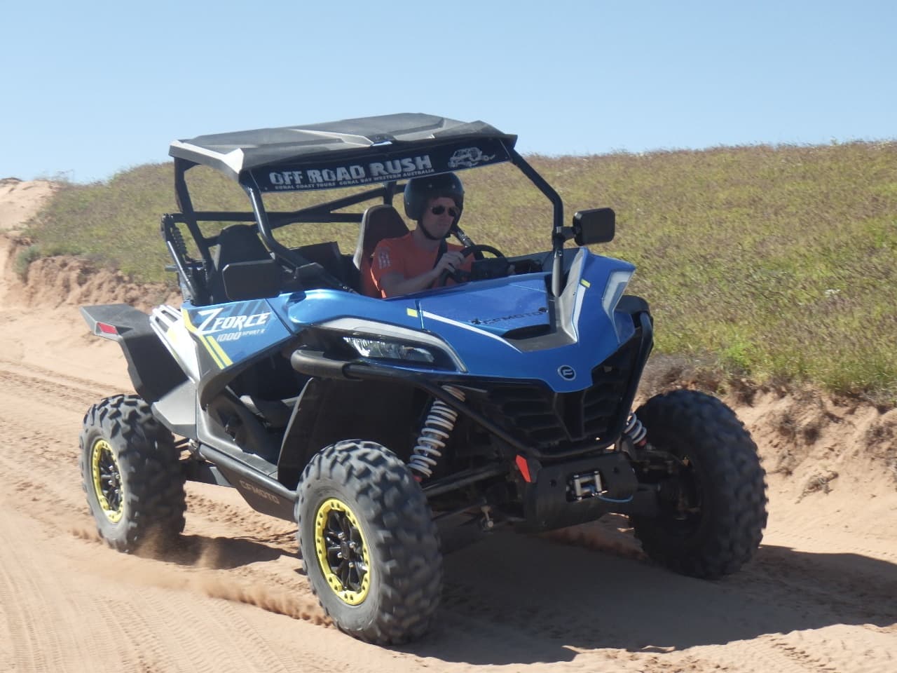 Off-road dune buggy driving on sandy coastal tracks in daylight
