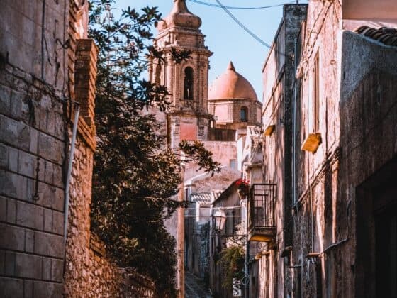 Historic narrow alley and church dome in sunlit Mediterranean town