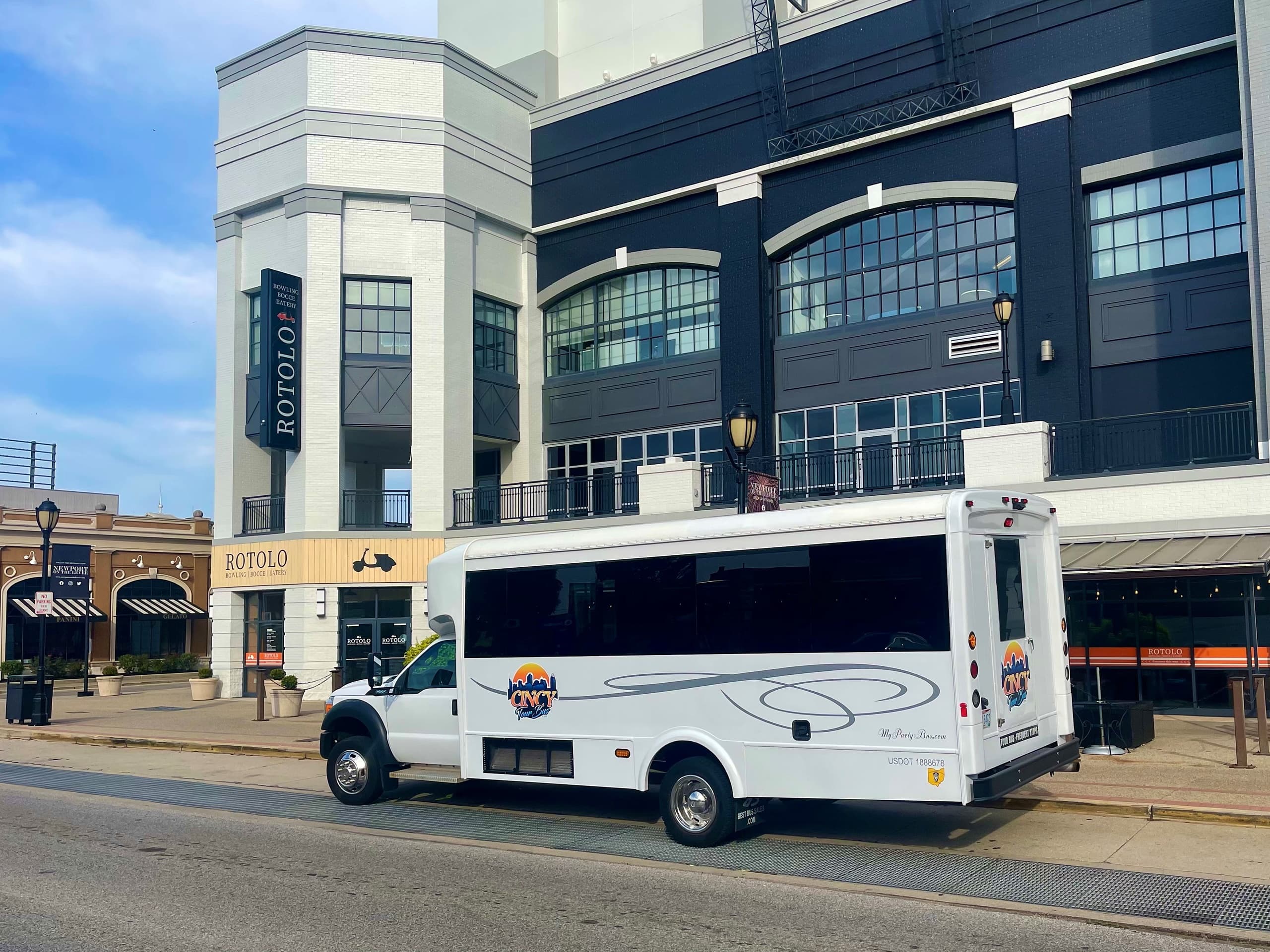 White tour bus parked by urban Cincinnati waterfront venue