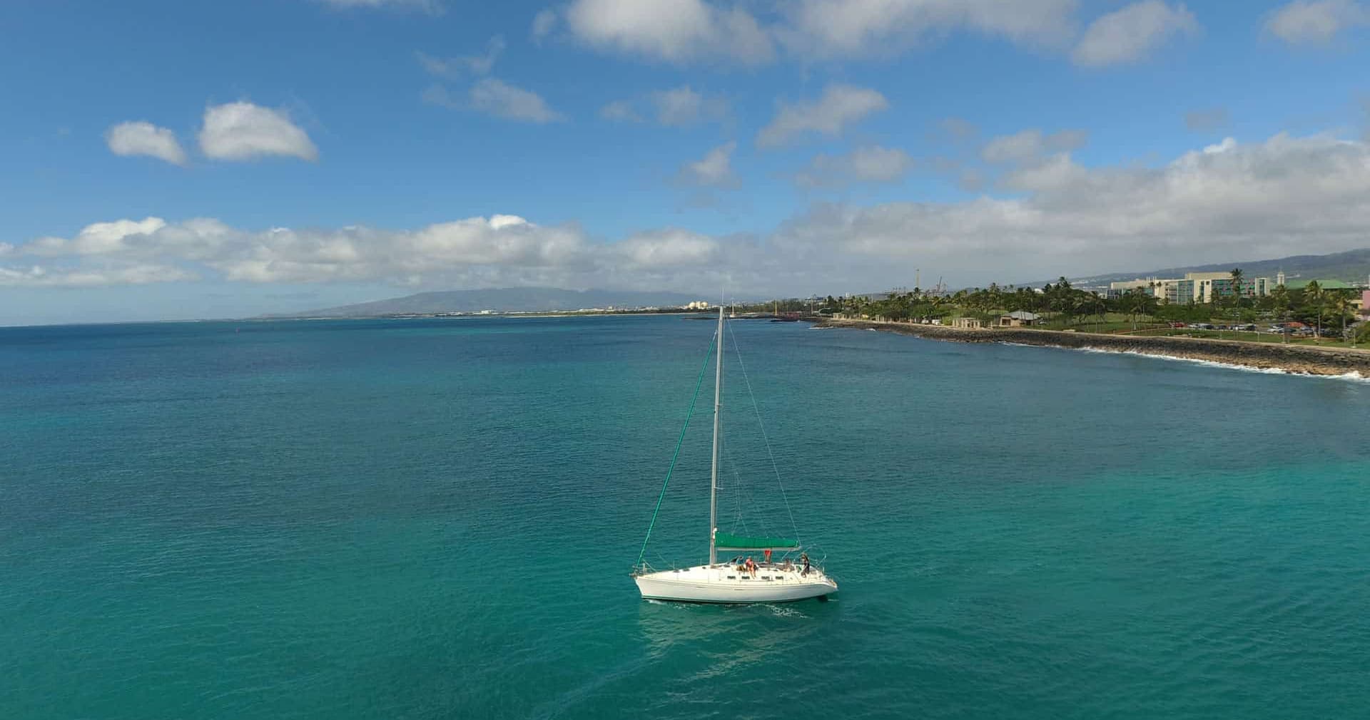 Single sailboat cruising turquoise waters off Honolulu coast