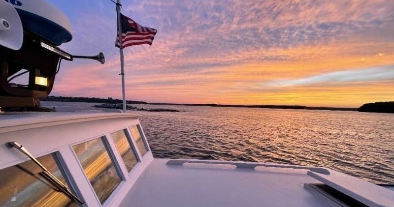 Boat bow with American flag cruising Casco Bay at sunset