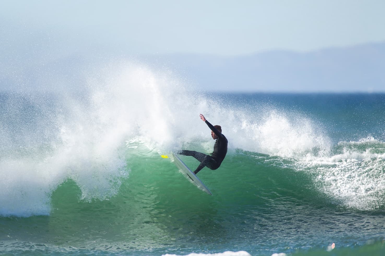 Surfer carving a green wave on coastal ocean reef
