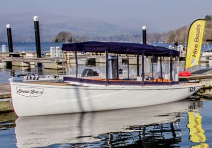 Covered leisure boat docked at marina with calm reflections