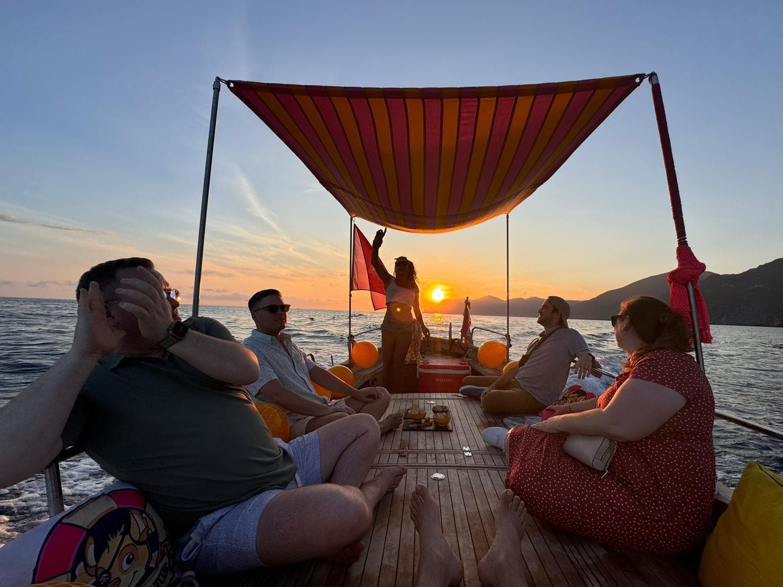 Sunset boat tour guests relaxing under canopy along Cinque Terre