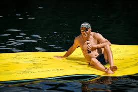 Man sitting on yellow inflatable water mat floating on lake