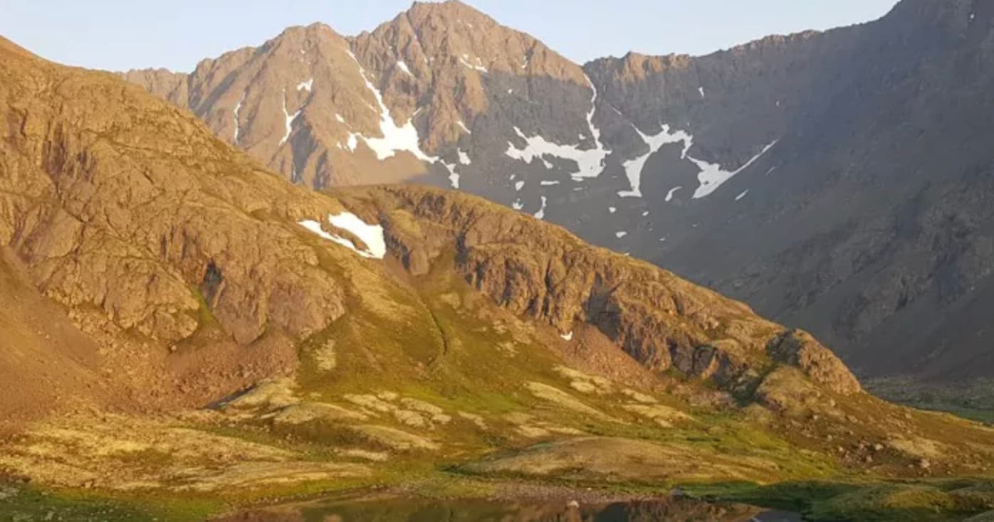 Golden-hour mountain range with hiking trails and ridgeline