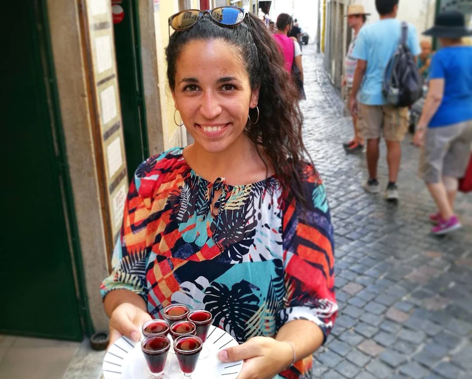 Local guide serving traditional ginjinha shots on Lisbon cobblestones