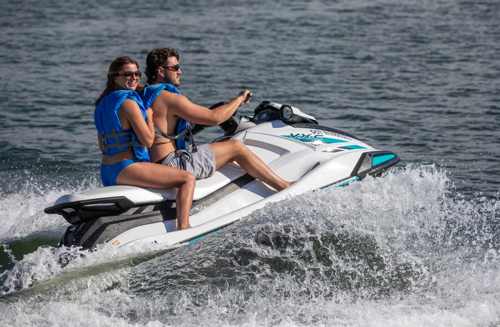 Couple riding jet ski across open sea, high-speed action
