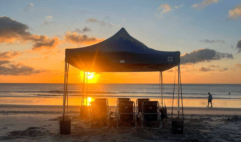 Oceanfront canopy tent glowing at sunrise on the beach