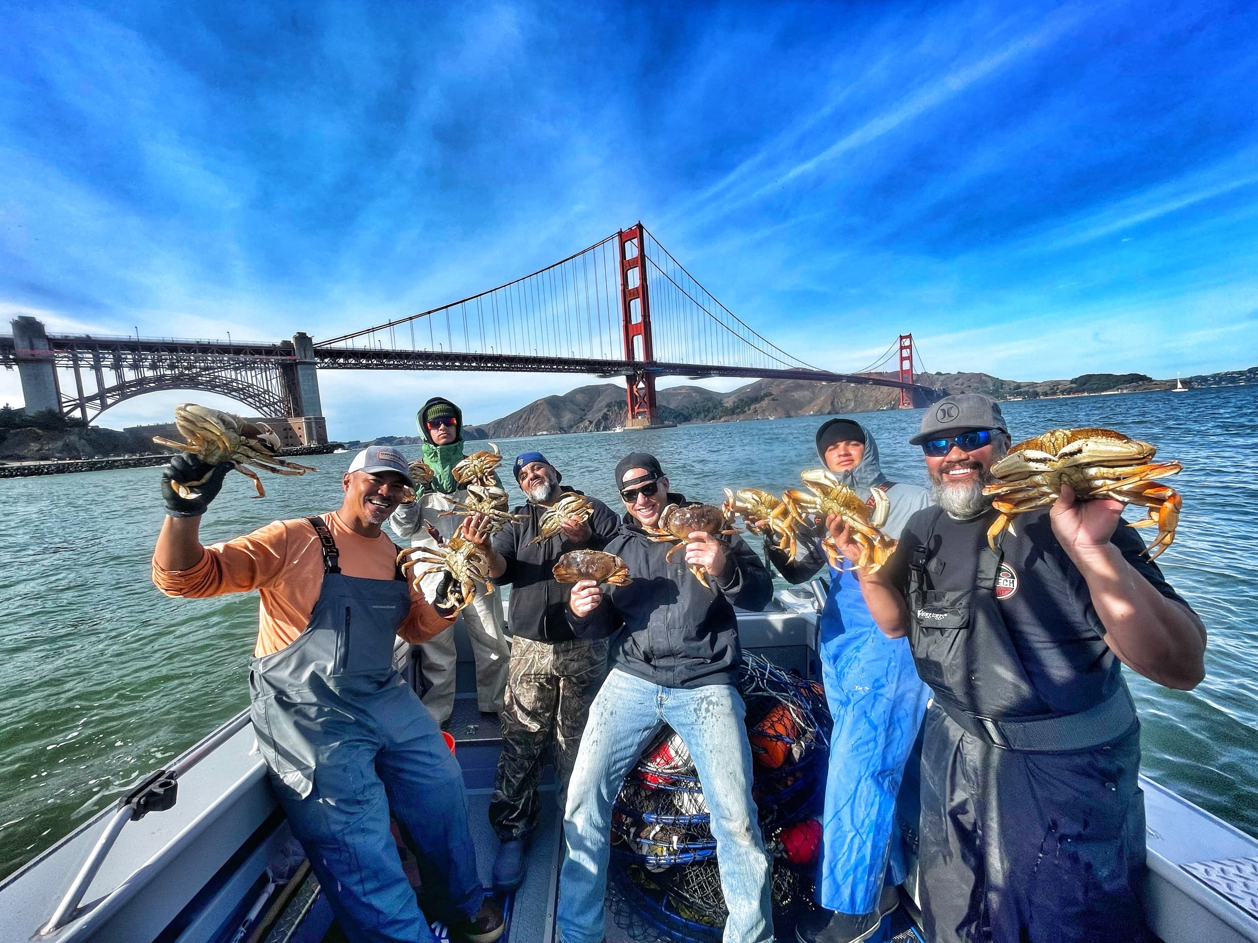 Fishermen holding Dungeness crabs under Golden Gate Bridge