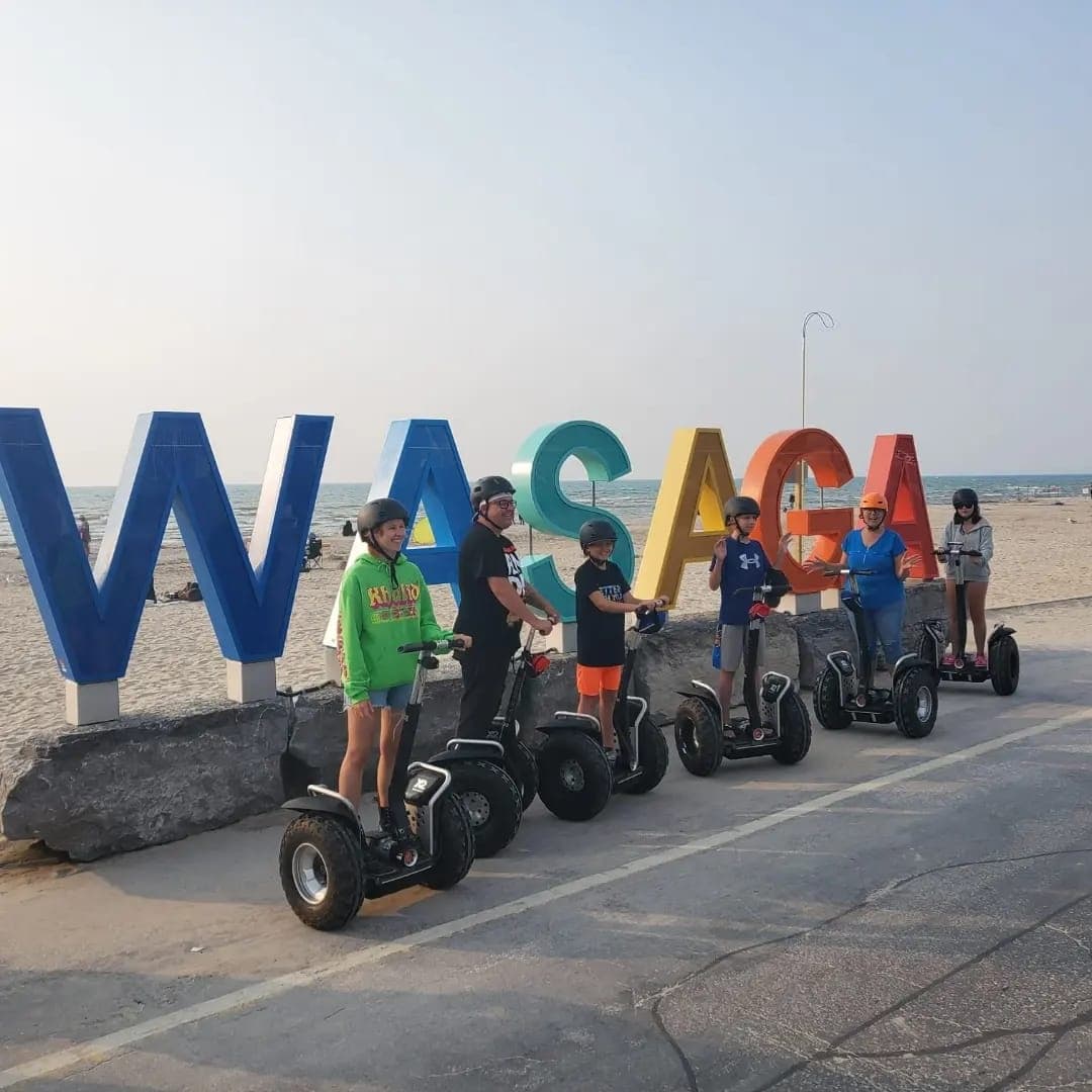 Segway tour group posing by WASAGA Beach sign on boardwalk