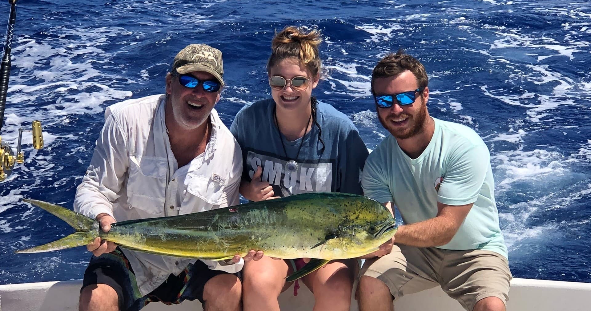 Anglers holding mahi-mahi on sportfishing boat in open ocean