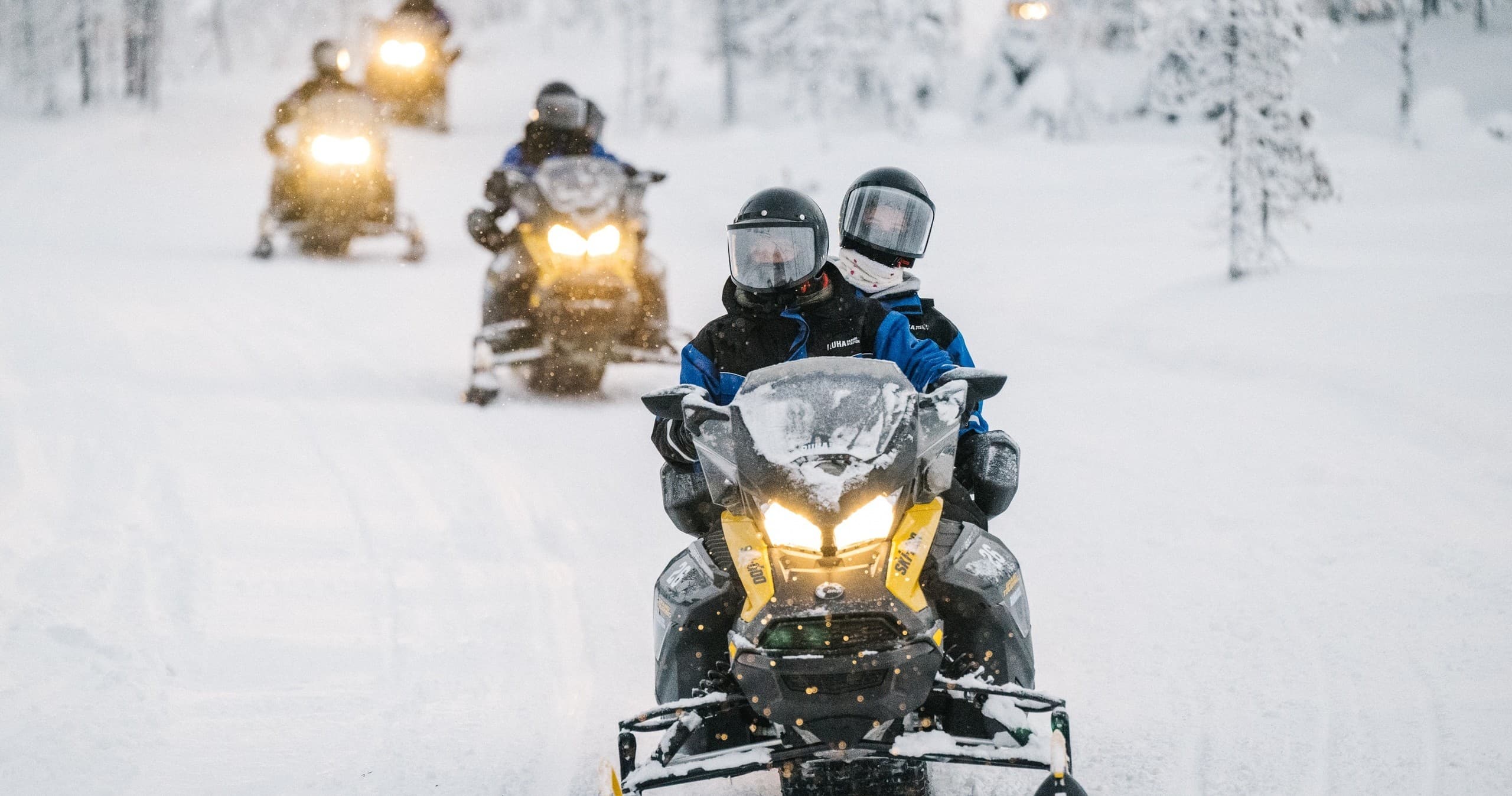 Guided snowmobile convoy touring snowy Lapland forest highway
