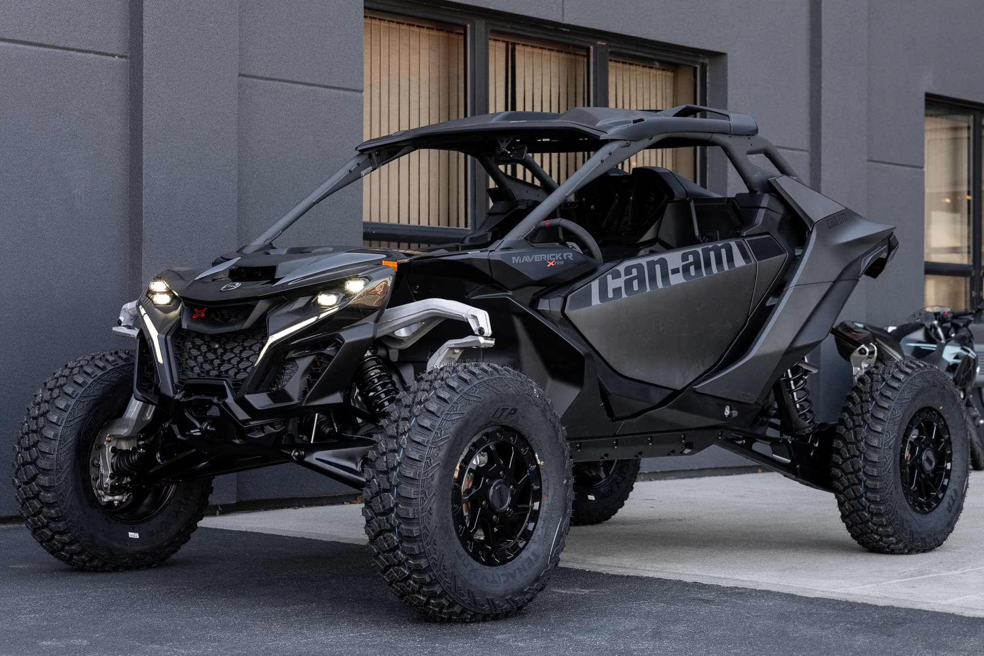 Black Can-Am off-road buggy parked outside urban garage for desert rides