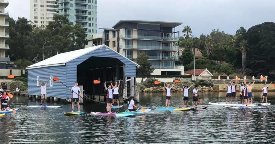 Group paddleboard lesson at waterfront boathouse on calm harbor