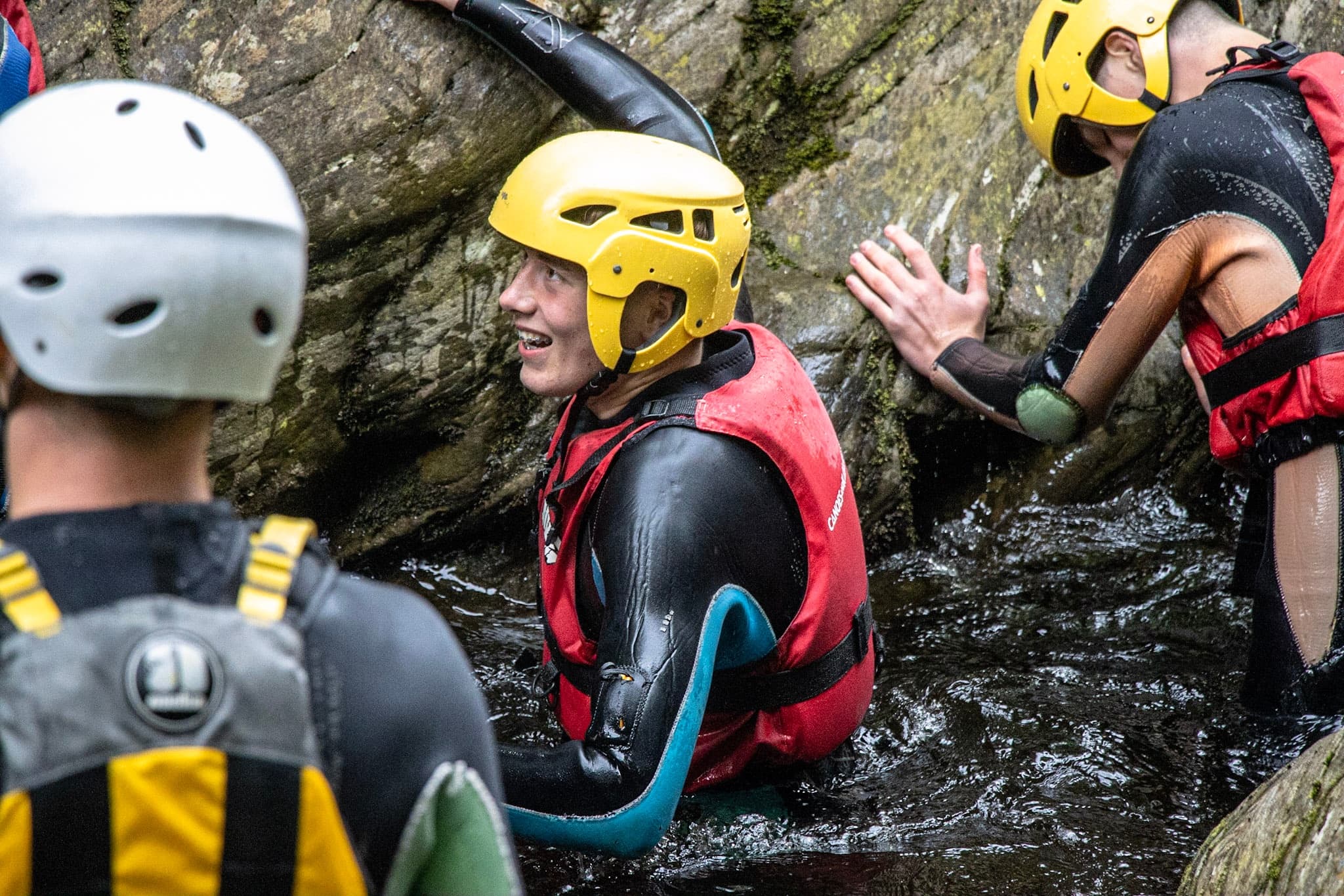 Group canyoning through a rocky river gorge wearing helmets