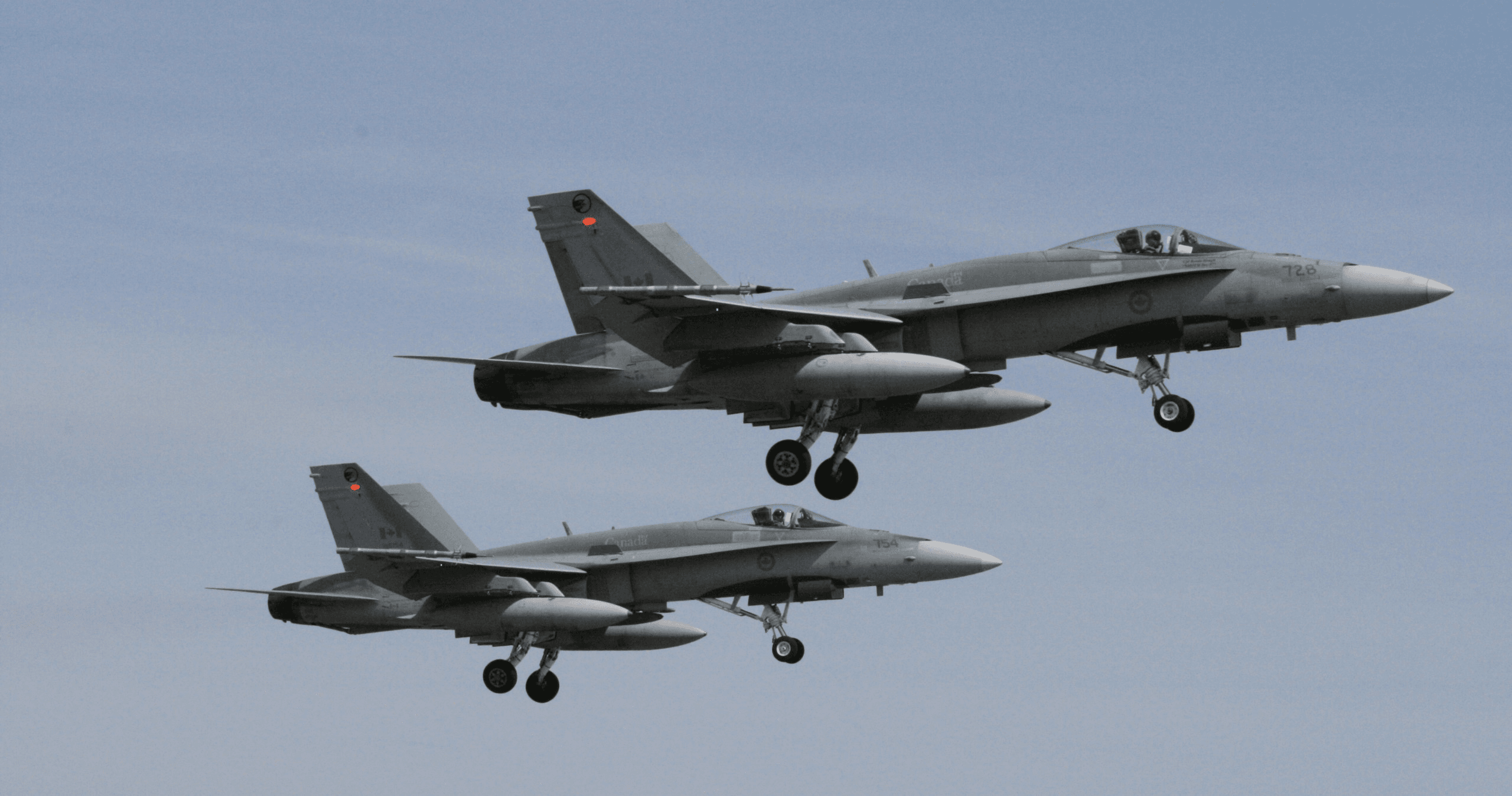 Two military jets mid-flight over coastal landscape, aerial action
