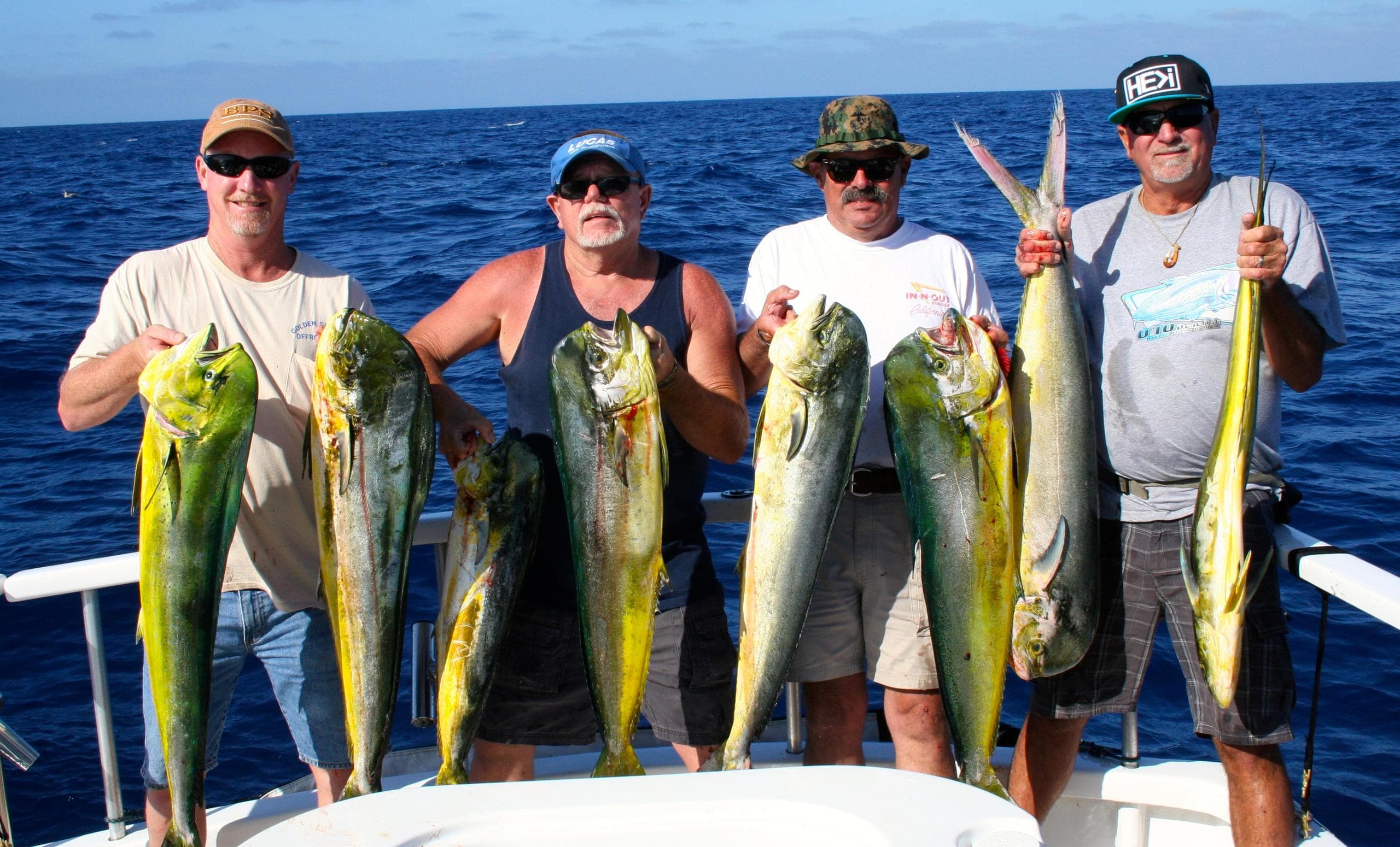 Anglers lined up with mahi mahi and tuna on sunny ocean