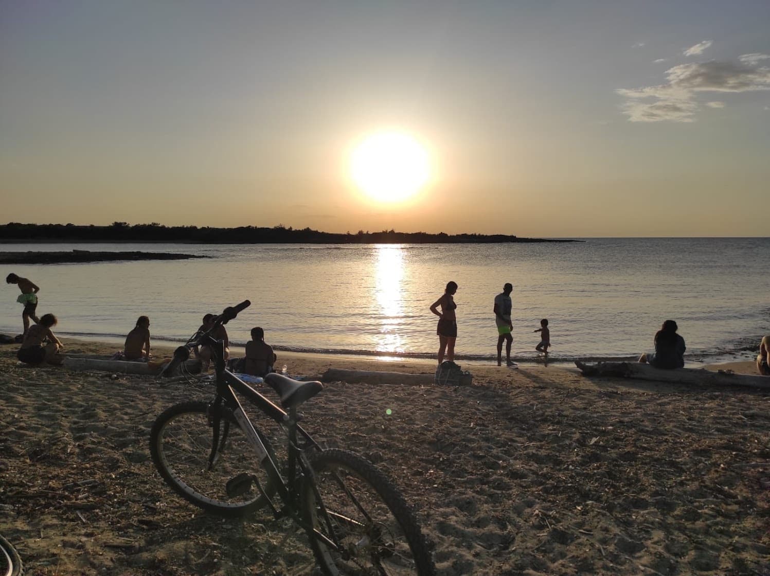 Beach sunset with bikes and people silhouetted by shoreline