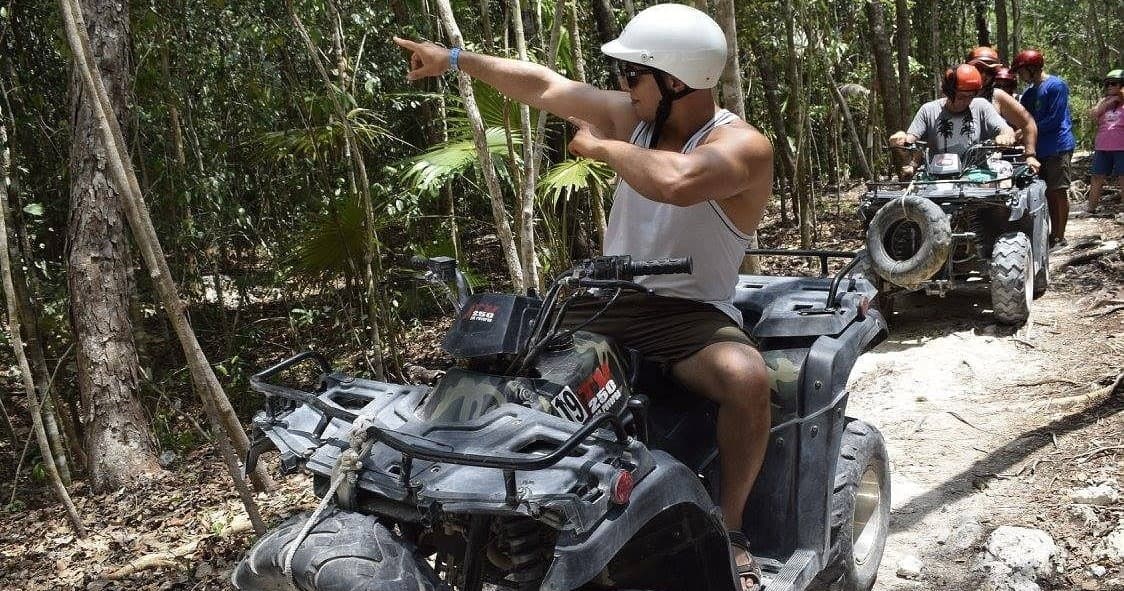 ATV rider pointing on tropical forest trail during guided tour