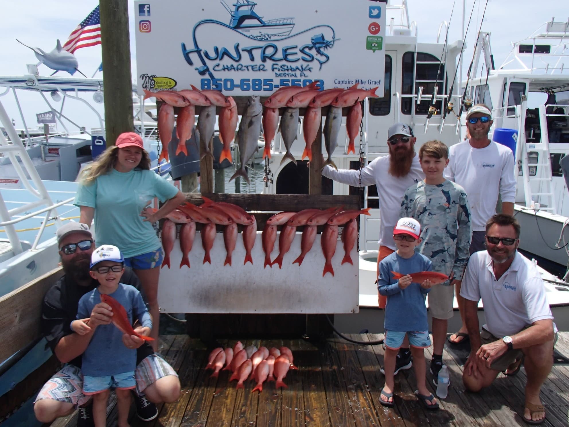 Family and anglers posing at marina with displayed redfish catch