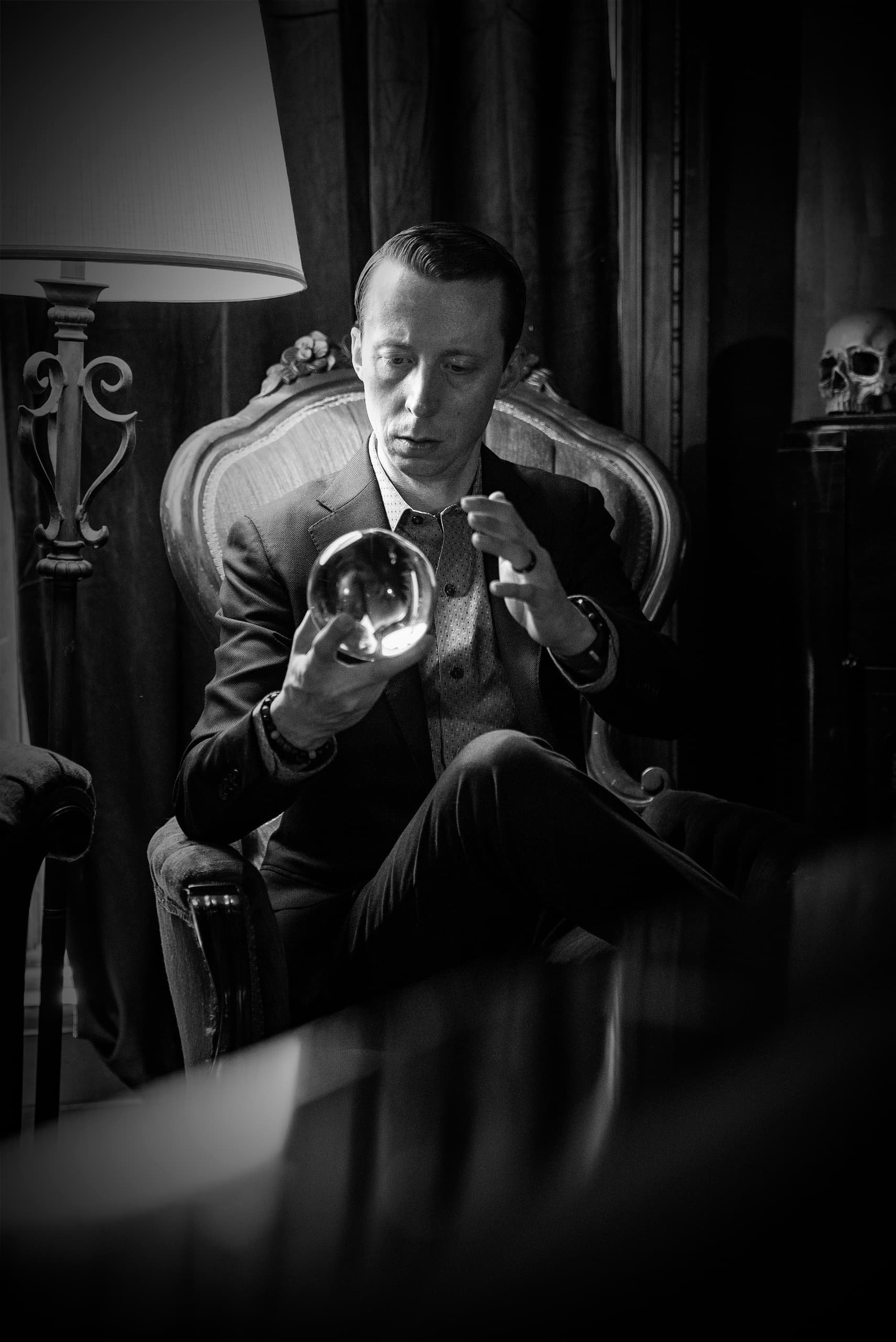 Black-and-white portrait of man examining crystal ball indoors