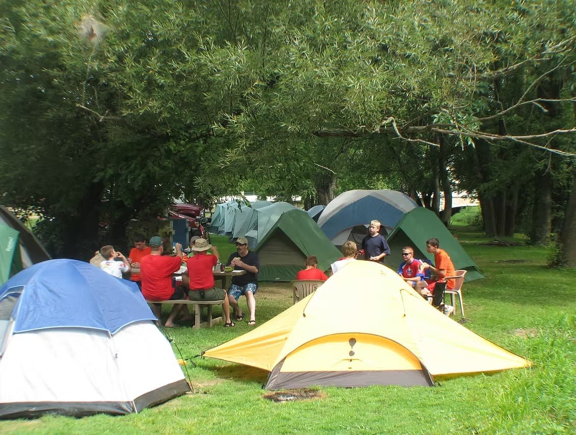 Group camping with tents on grassy riverside campground