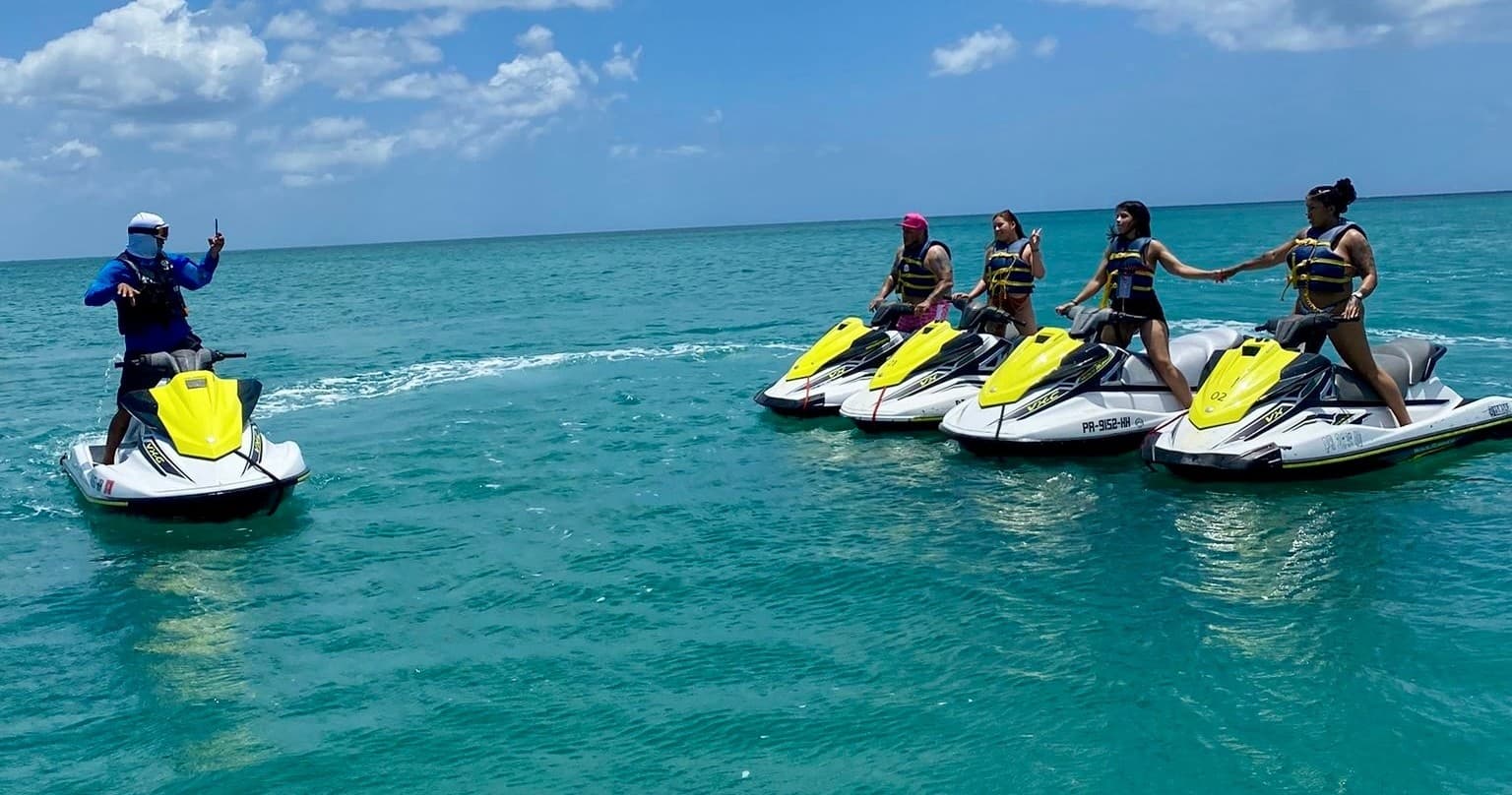 Group riding jet skis on turquoise ocean near tropical shore