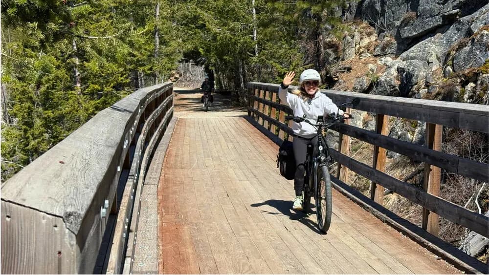 Cyclist crossing wooden bridge on forested mountain trail