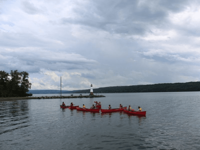 Group of red kayaks silhouetted on open lake at dusk