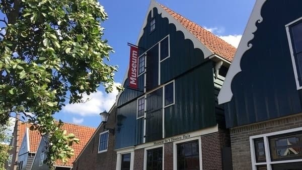 Traditional Dutch wooden houses by street, museum visitor scene