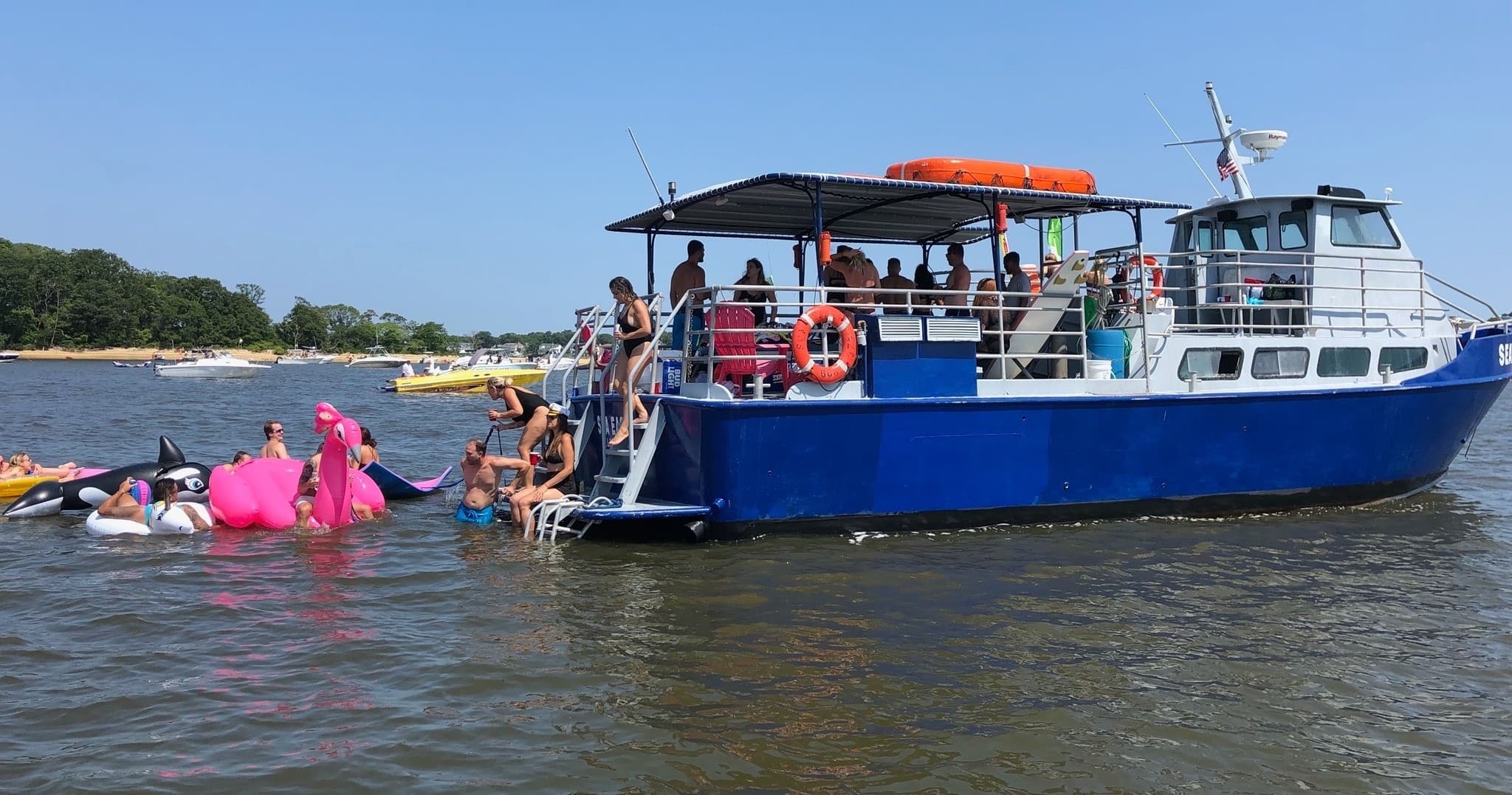 Party boat with swimmers and inflatables on coastal bay