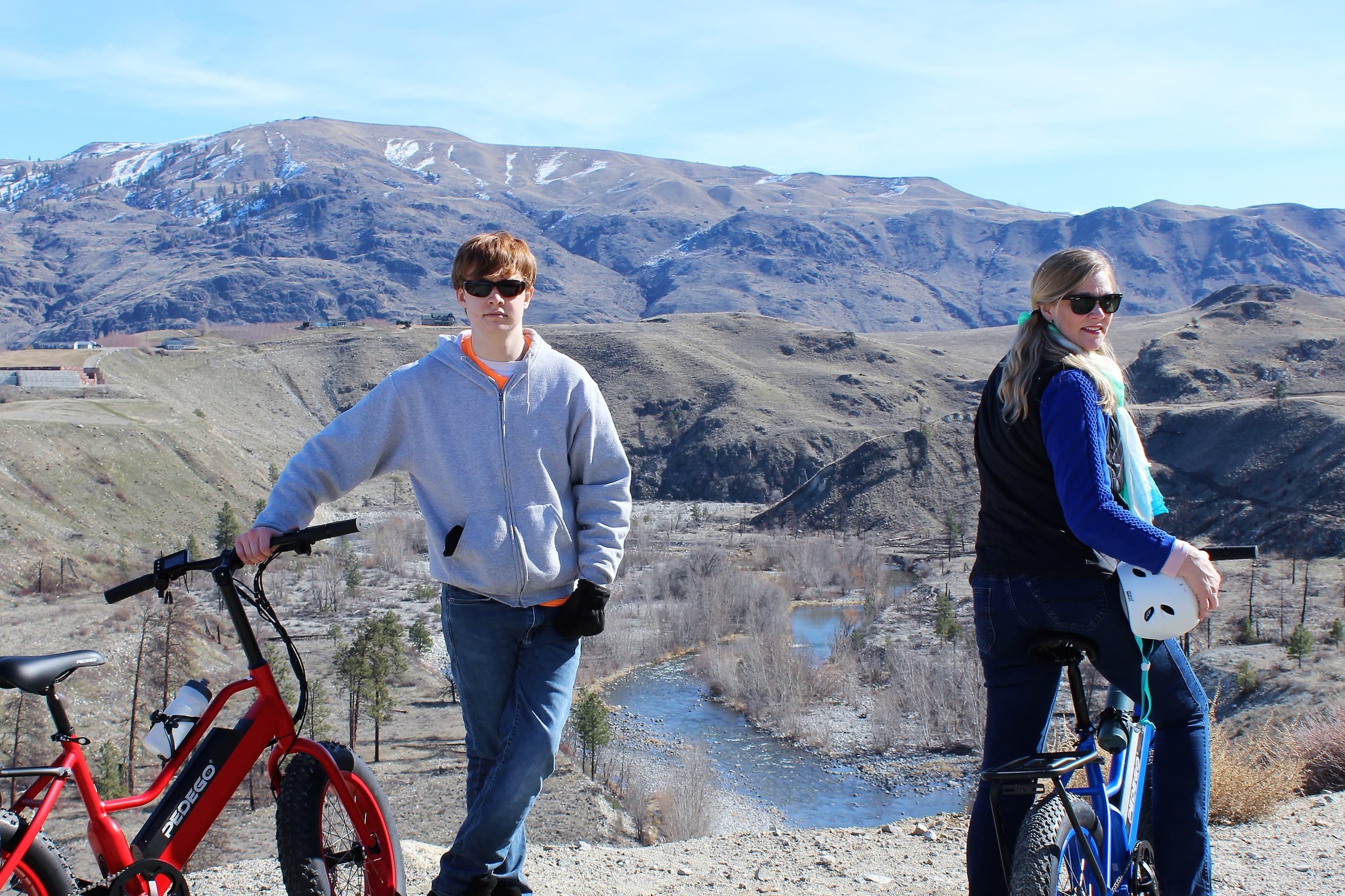 Two riders paused with electric bikes overlooking river canyon vista