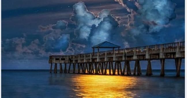 Sunset pier over ocean, coastal paddleboarding and scenic vista