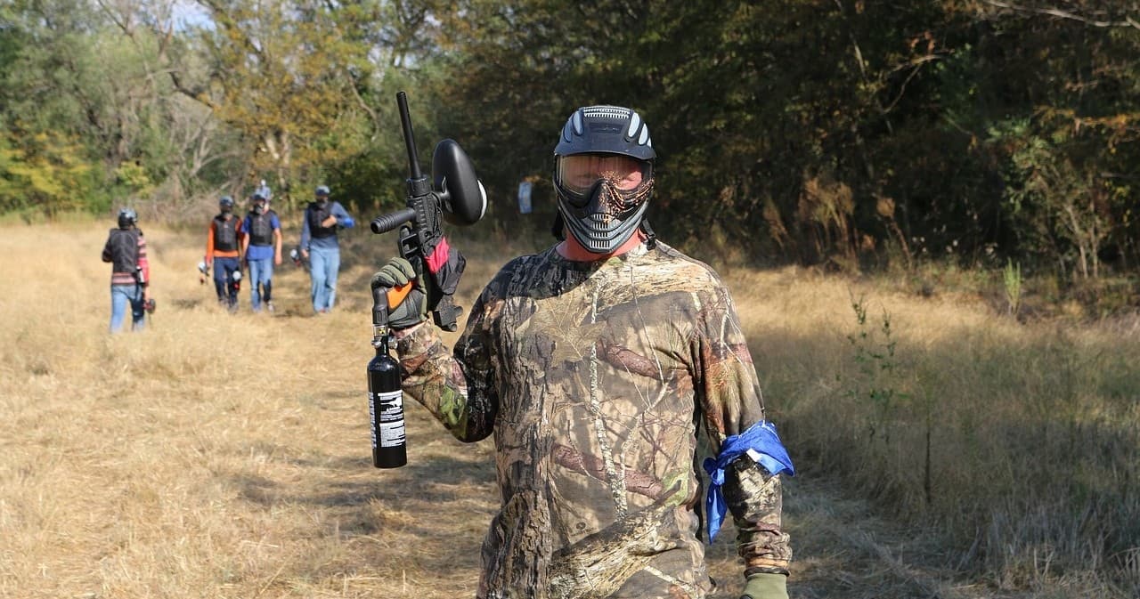 Players walking across outdoor woods paintball course