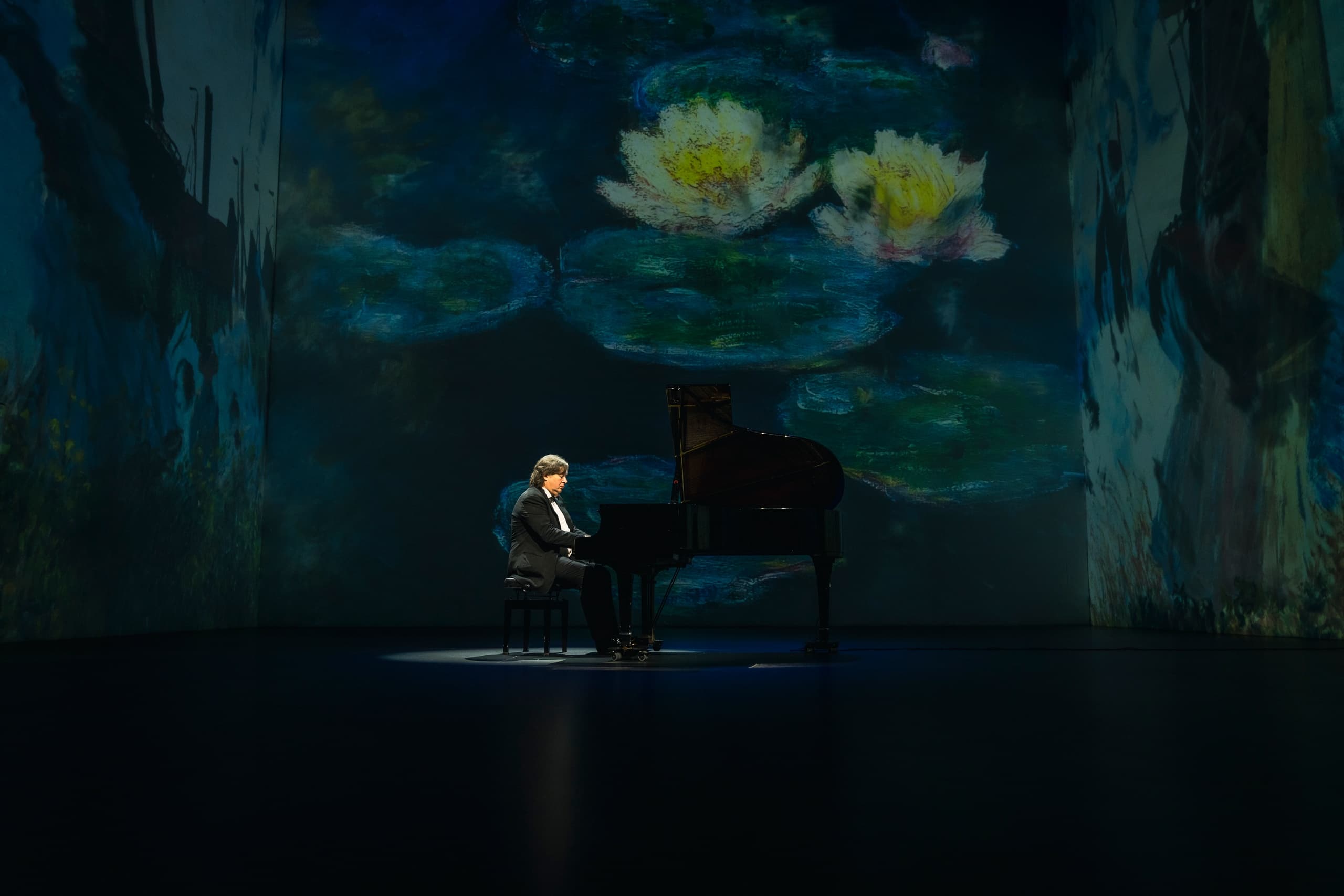 Pianist performing before giant waterlily mural, moody theater scene