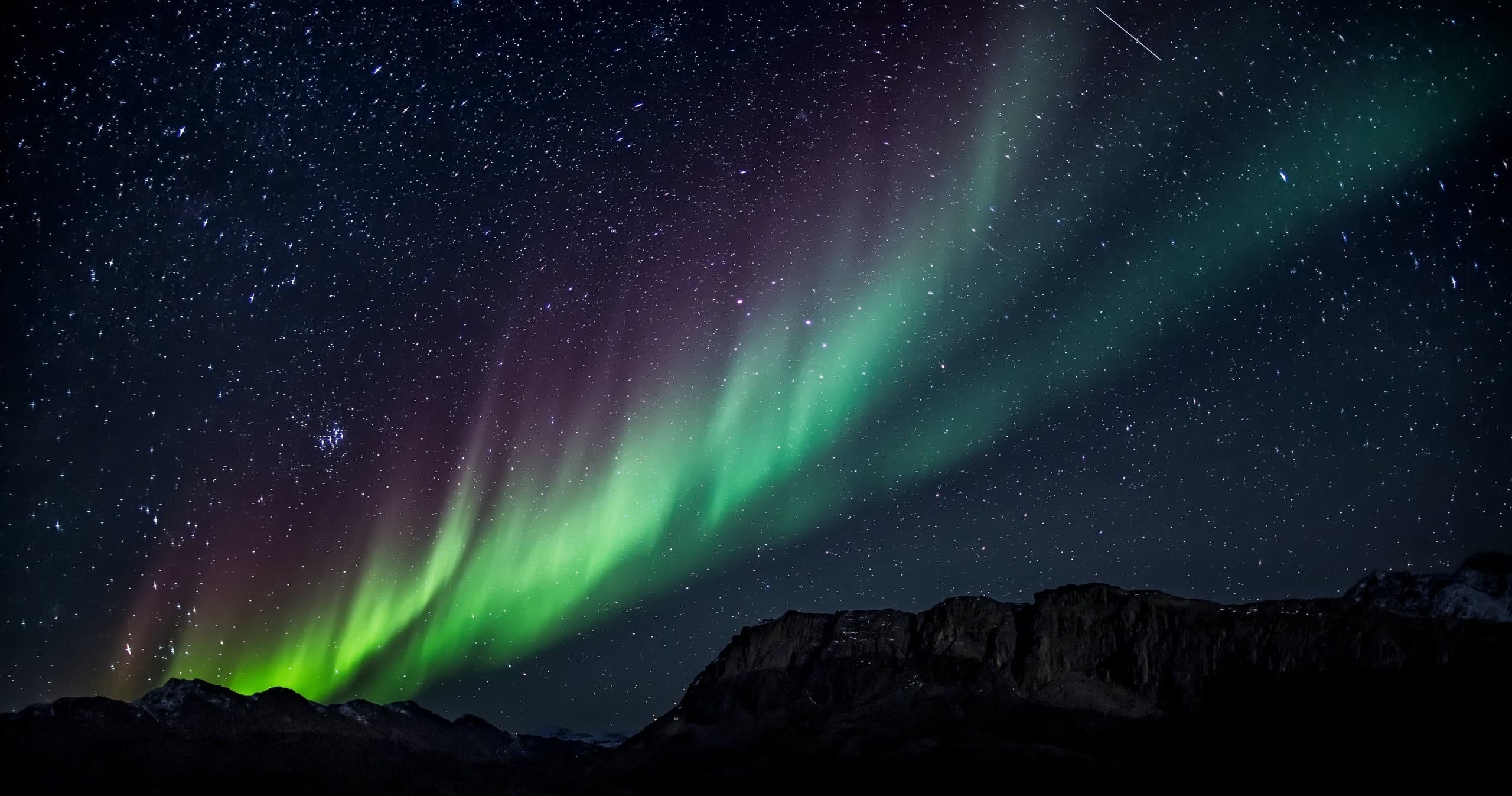 Northern Lights over mountain range at night, aurora viewing